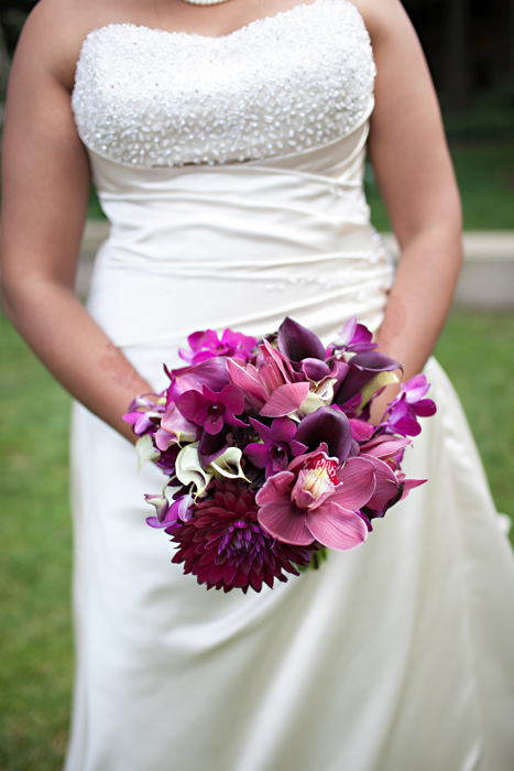 bride ins a white wedding dress with a purple orchid bouquet