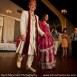 Indian bride in a hot pink wedding lehenga and a groom in a sherwani walking in